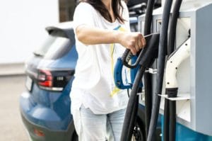Woman charge Electric car on gas station. Blue car and electric