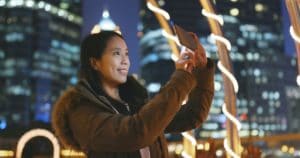 Woman taking photo on smart at night with city background